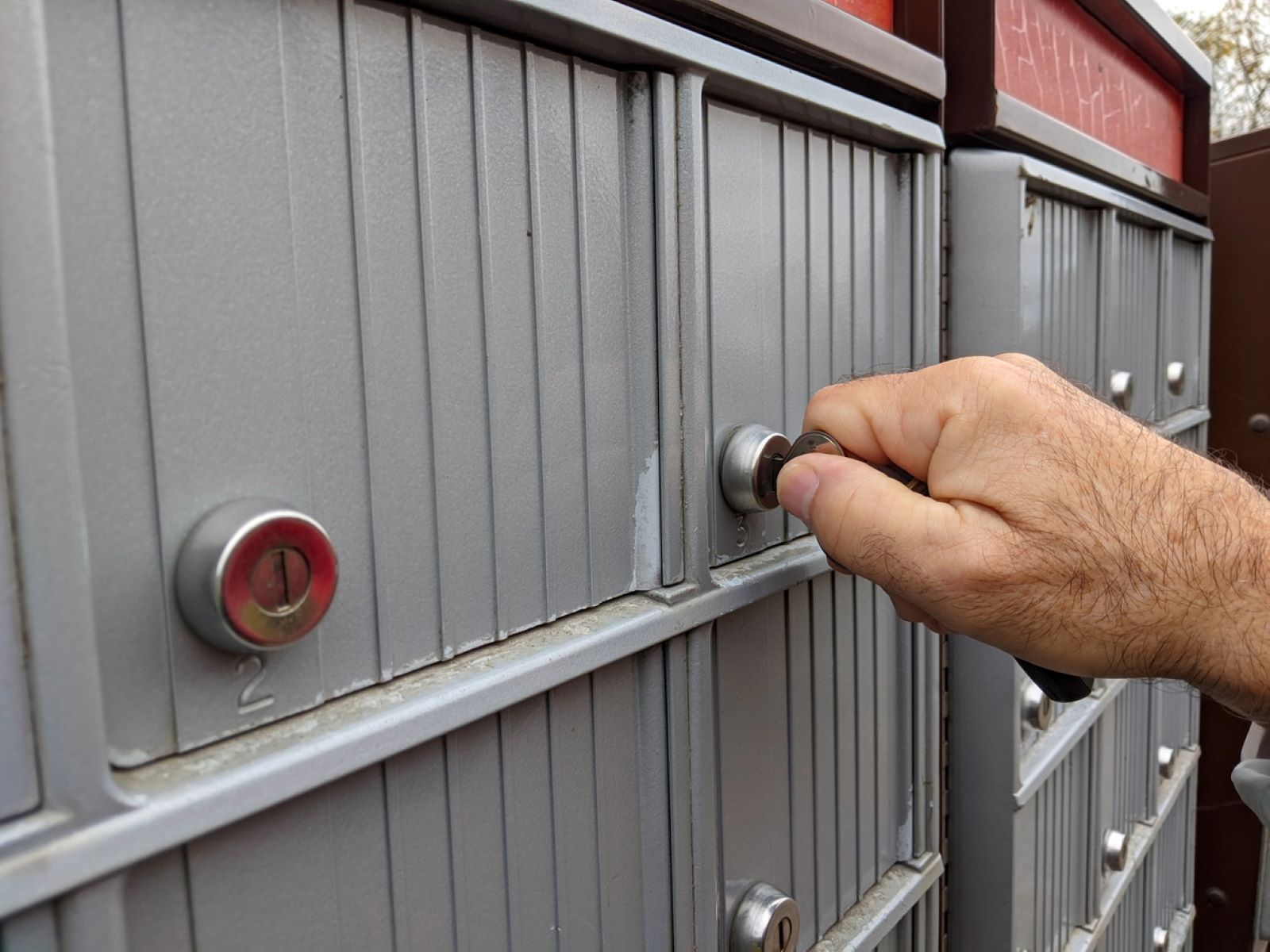 person opening mail box unit with key